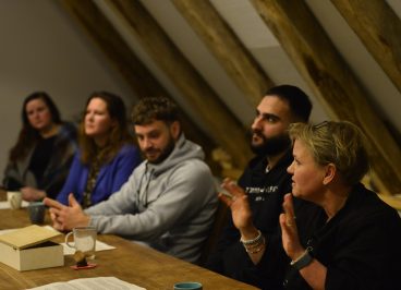 mensen aan tafel 1 vrouw praat en anderen luisteren