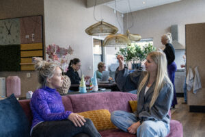 2 medewerkers op de bank in gesprek, andere collega's op de achtergrond